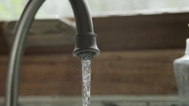 Mutfakta musluk, yavaşça bir damla su damlatıyor.