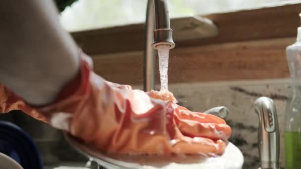 Handen in oranje handschoenen afwassen in de keuken. Sluiten. — Stockvideo