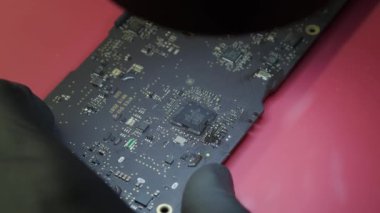 Tamir atölyesindeki elektronik tadilatın makro görüntüsü, dizüstü bilgisayarın ana kartında bir elektrik parçası.