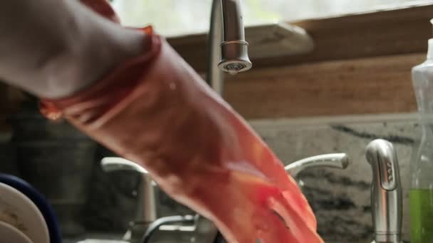 Ręce w pomarańczowych rękawiczkach zmywają naczynia w kuchni. Zbliżenie strzału — Wideo stockowe