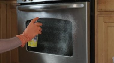 Sarı lastik eldivenli bir adam elektrikli fırın sapını temizliyor. Kapat.