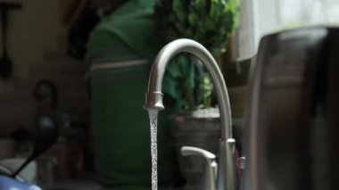 Turuncu eldivenli eller mutfakta bulaşıkları yıkar. Kapat.