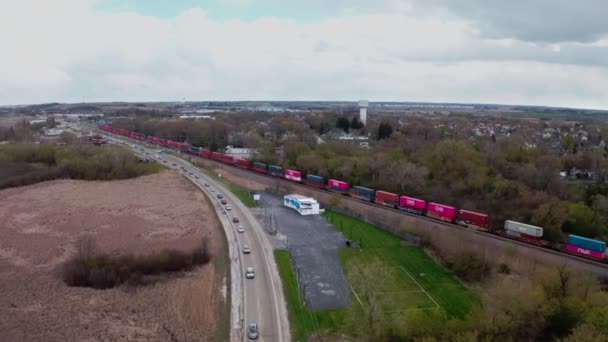 Aerial viiew of Locomotive with freight railway wagon rides on railroad. Transportation and delivery of cargo in containers between cities. Aerial drone view over train riding through forest — Stockvideo