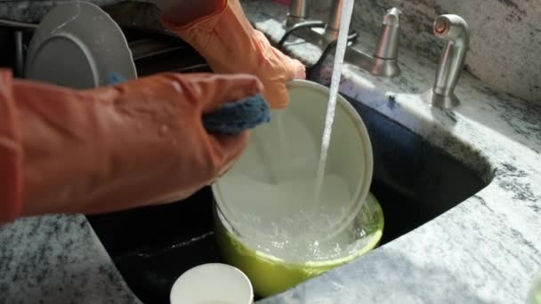 Vue sur les mains en gants orange laver la vaisselle dans la cuisine. Mouvement lent — Video
