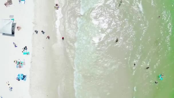 Kumsala çarpan okyanus dalgalarının yukarıdan aşağıya insansız hava aracı görüntüsü. İnsanlar güneşli bir yaz gününde kumlu plajı severler. . — Stok video