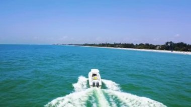 Mavi denizde ya da okyanusta yüzen sürat teknesi. Derin sularda yarışan lüks yatın havadan görünüşü. Çekimin üstünde