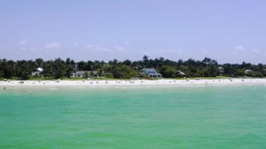 Okyanus dalgalarının sahile çarptığı hava aracı görüntüsü. İnsanlar güneşli bir yaz gününde kumlu plajı severler. .