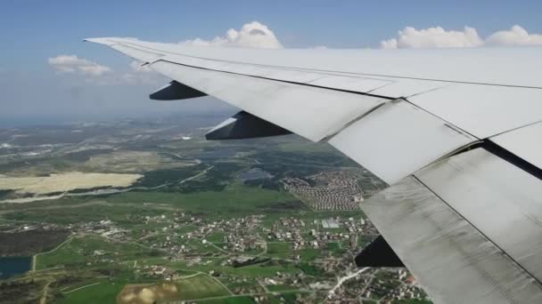 Крыло самолета и облака и земля с поселениями, вид изнутри самолета. — стоковое видео
