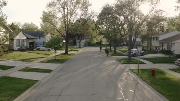 Vista aérea del avión no tripulado de la familia que monta una bicicleta en las calles de los suburbios en tiempo soleado. — Vídeos de Stock