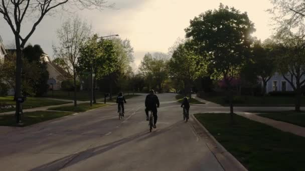 Снимок семьи с беспилотника на велосипеде на улицах пригородов в солнечную погоду. — стоковое видео