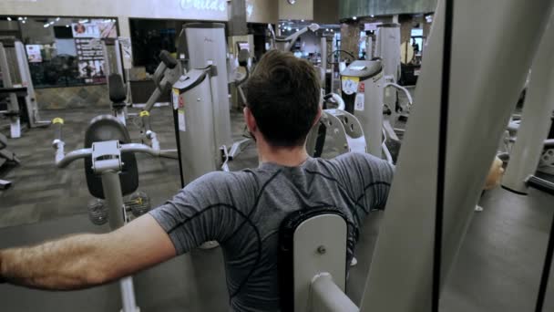 Modernes Fitnessstudio, ein Typ, der sich auf das Trainingsgerät setzt und trainiert. Zeitlupen-Futage — Stockvideo