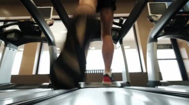 Man 'in koşu pistinde yürüdüğü, koşu bandında ısındığı yakın plan. Yavaş çekim 