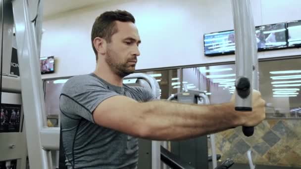 Slow motion shot. Modern gym, a guy sitting down on the training apparatus and training. — Stock Video