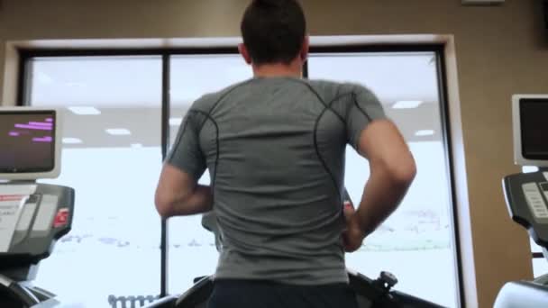 Man walking on running track, warming up on gym treadmill. Back view and Slow motion — Stock Video