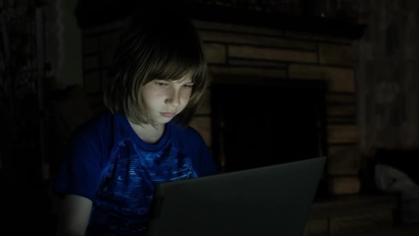 Un niño pequeño compra en Internet. sentado en el suelo con un ordenador portátil por la noche — Vídeo de stock