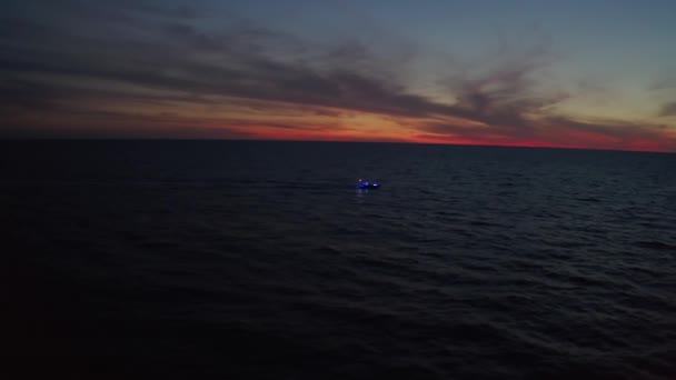 Yacht navigue sur des nuages lumineux colorés pendant le coucher du soleil sur la mer ou l'océan, vue aérienne sur les drones. — Video