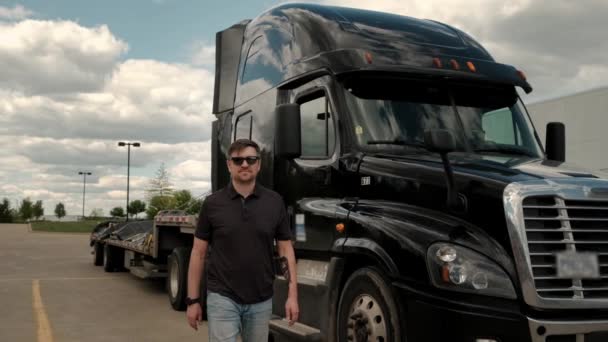 Portrait of Professional Truck Driver approaches his truck and crosses his arms Behind Him Parked Long Haul Semi-Truck with Cargo Trailer — Stock Video