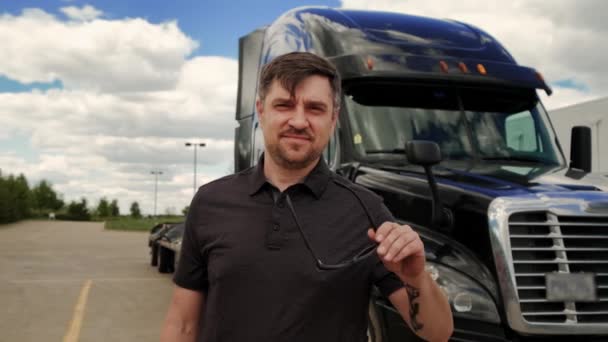 Motorista de caminhão profissional usa óculos de sol atrás dele estacionado Long Haul semi-caminhão com reboque de carga — Vídeo de Stock