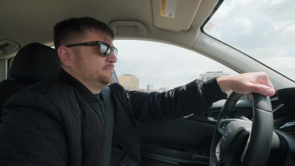 Vue de l'homme conduisant une voiture dans la journée, main sur le volant, plan large — Video