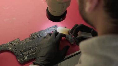 Elektronik yenileme atölyesinde yakın çekim, ana kartta elektrik parçası var. Üst görünüm