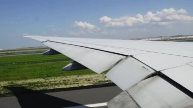 Havaalanından kalkan uçağın yolcu kabini penceresinden havaalanını izliyoruz. Yavaş çekim gelecek