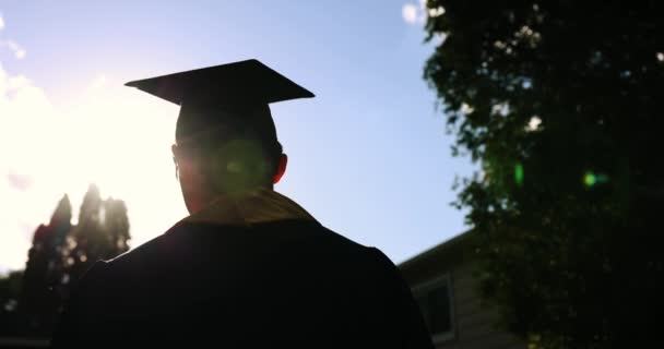 Primer plano Vista trasera del estudiante graduado universitario en la puesta de sol Silhouette — Vídeos de Stock