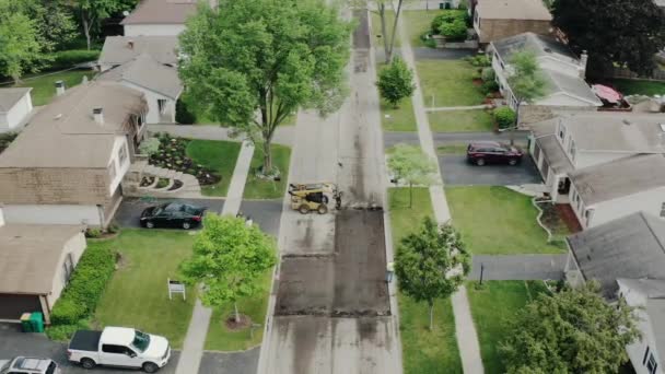 Vue aérienne par drone des réparations routières dans les banlieues, dans la rue avec de nombreuses maisons — Video