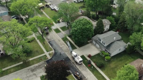 Vista aérea drone de reparos rodoviários nos subúrbios, na rua com muitas casas, colocação de novo asfalto — Vídeo de Stock