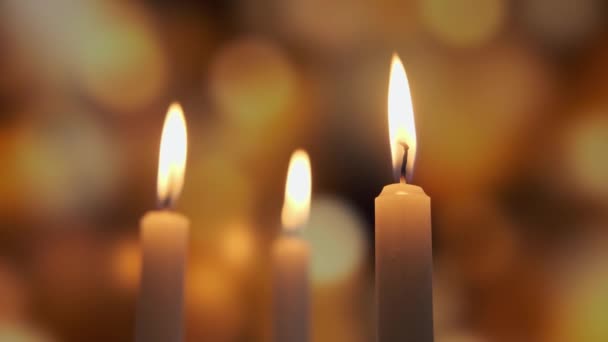 Footage of burning a three candles on on a yellow background of colored blurred bokeh. Close up view — Stock Video