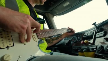 Kamyon şoförü takside oturup gitar çalarken yakın çekim.
