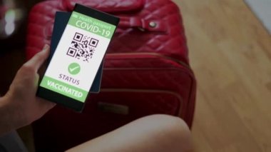 Cep telefonundaki aşı pasaportu bavulda seyahat olanağı sağlıyor. Üst görünümü kapat