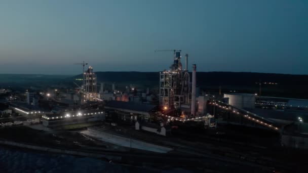 Planta de cemento con alta estructura de fábrica en el área de producción industrial por la noche con las luces encendidas. Vista aérea del dron — Vídeos de Stock