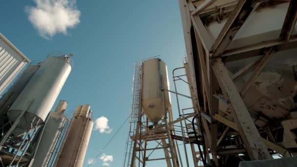 Edificios de fábricas de cemento y grandes embalses con materiales contra la ciudad industrial a pie de colinas. Amplio tiro — Vídeos de Stock