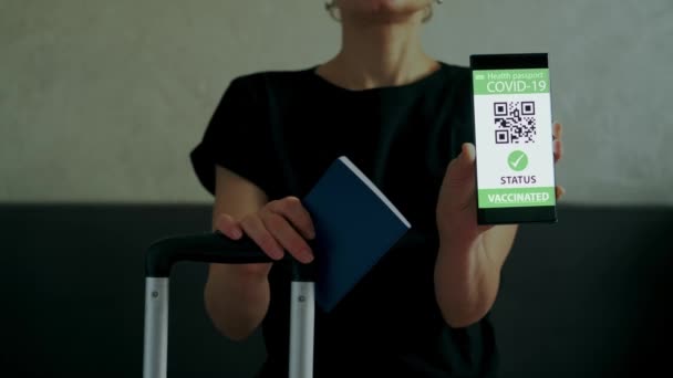 女人们展示了带有接种护照的智能手机，可以在手提箱中旅行。近景 — 图库视频影像