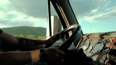 Kapatın. Kamyon şoförü, sıcak yaz gününde yoldaki kargoya gidiyor ve aynada güneş ışığı yansımaları var. Yavaş çekim