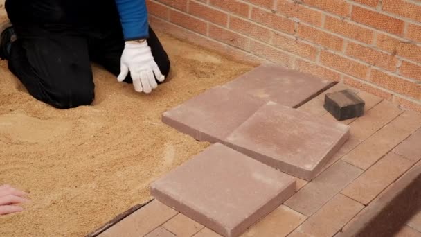 Trabajador profesional pone baldosas en la arena prensada. Vista en cámara lenta — Vídeos de Stock