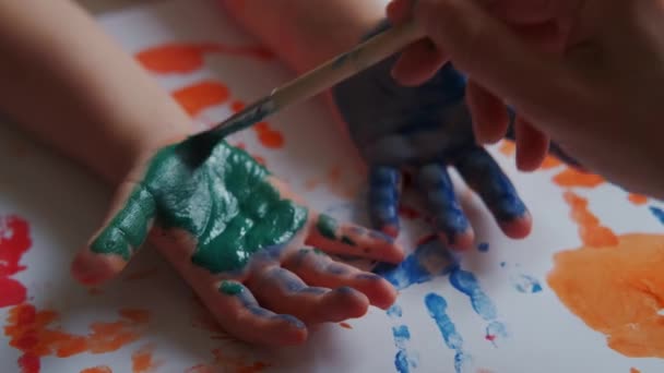 Mama maluje ręce dzieci kolorowymi farbami — Wideo stockowe