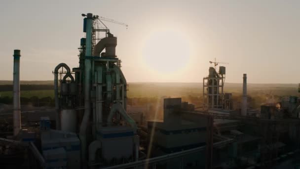 Um drone aéreo disparado. Fábrica de cimento com alta estrutura de fábrica na área de produção industrial ao pôr do sol. — Vídeo de Stock