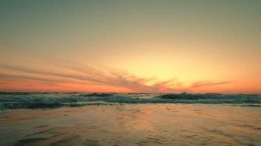 Dramatik deniz gündoğumunun geniş bir görüntüsü. Yavaş çekim yanan gökyüzü ve parlayan altın dalgalar.