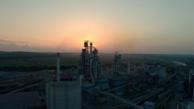 Hava aracı atışı. Güneşli bir günde günbatımında endüstriyel üretim alanında yüksek fabrika yapısına sahip siluet çimento fabrikası