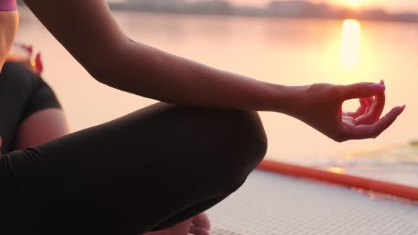 Ung kvinna som gör yoga på sup board vid solnedgången. Närbild — Stockvideo