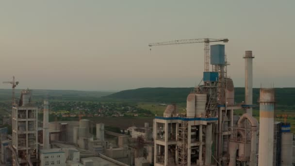 Cementfabriek met hoge fabrieksstructuur op industrieel productiegebied bij zonsondergang. Een drone schot. — Stockvideo