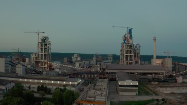 Planta de cemento con alta estructura de fábrica en el área de producción industrial al atardecer. Futage de vista aérea Drone — Vídeo de stock