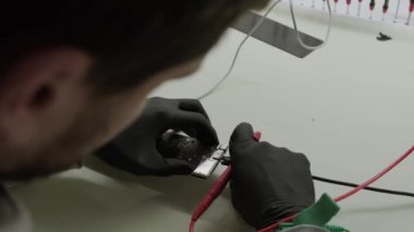 Electronic renovation in repair shop, testing electric current in the motherboard using multimeter. Slow motion