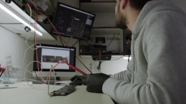 Electronic renovation in repair shop, testing electric current in the motherboard using multimeter. Wide shot