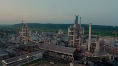 Gün batımında endüstriyel üretim alanında yüksek fabrika yapısına sahip çimento fabrikası. Drone görünümü Futage 4k