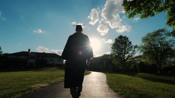 Rückansicht des Studenten der Universität bei Sonnenuntergang Silhouette geht auf die Straße. Zeitlupe — Stockvideo