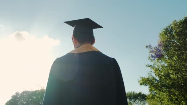 Silhouette Günbatımında üniversite mezunlarının dikiz görüntüsü yolda devam ediyor. Yavaş çekim. — Stok video
