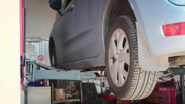 Автомобиль на автоподъемнике поднимается для диагностики и ремонта — стоковое видео