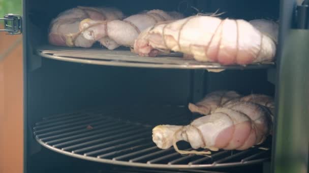 O homem põe a carne de aves no fumeiro. — Vídeo de Stock